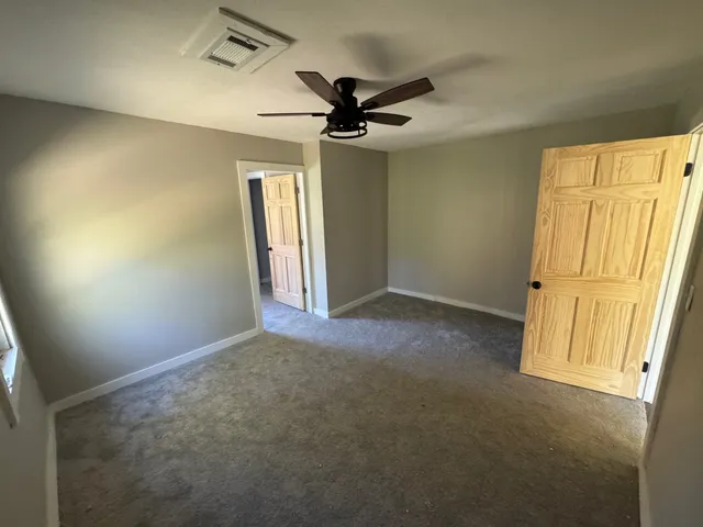 an empty room with windows and fan