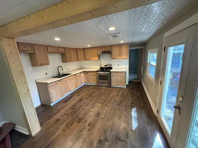 a large kitchen with a sink and wooden floor