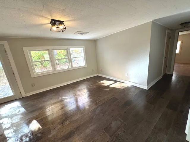 an empty room with wooden floor and windows