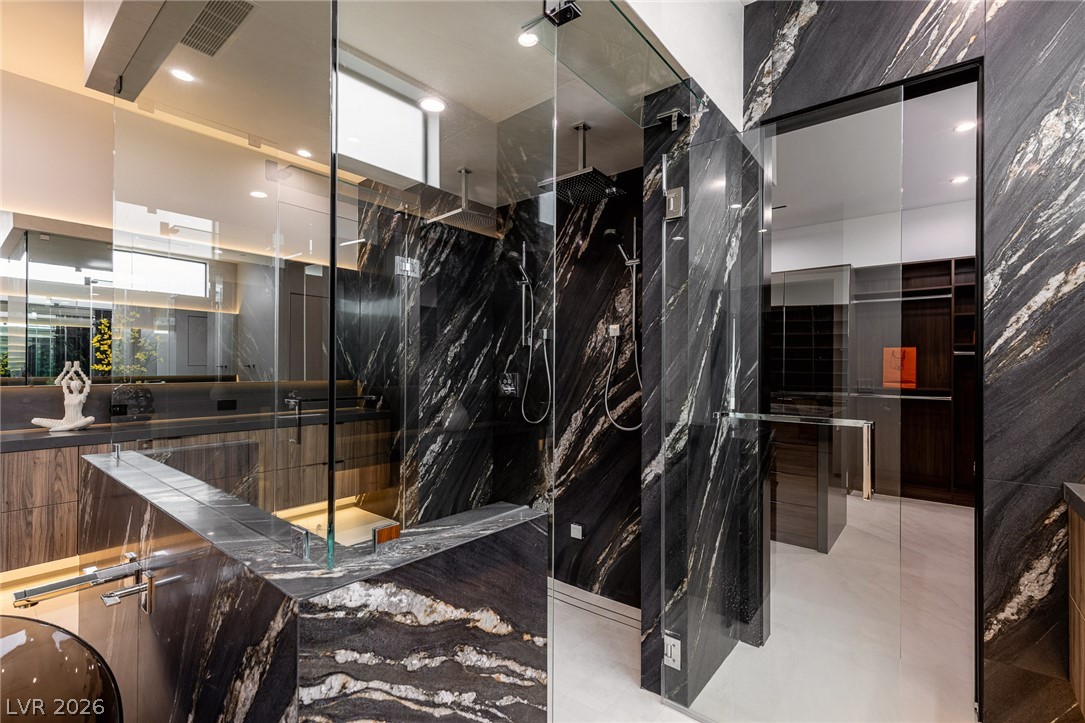 563 Grand Rim Drive Henderson, NV 89012 - Photo 24 of 70 Luxurious black stone and glass enclose a spacious shower, reflecting the adjacent vanity and dressing area.