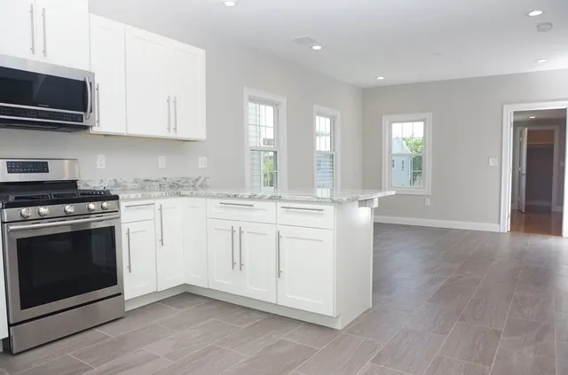 a kitchen with granite countertop a stove a sink and a microwave