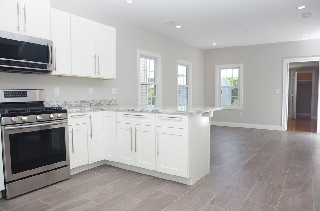 6 Florence Street, Unit 2 Somerville, MA 02145 - Photo 3 of 8 a kitchen with granite countertop a stove a sink and a microwave