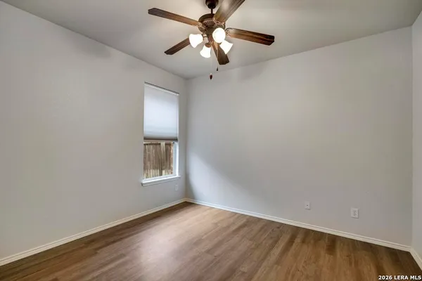 a view of an empty room with window and wooden floor