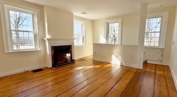 a view of empty room with wooden floor and fireplace
