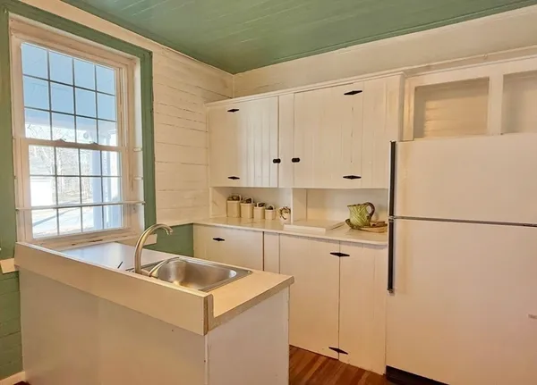 a kitchen that has a refrigerator a sink and white cabinets
