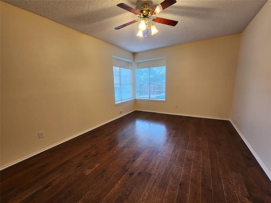 2413 Timber Ridge Lane Flower Mound, TX 75028 - Photo 16 of 32 Spacious room featuring rich wood-finish flooring, a corner window configuration, and a ceiling fan with integrated lighting