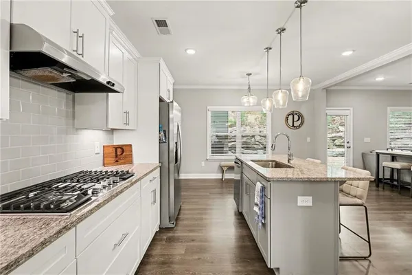 a kitchen with kitchen island a counter space a sink stainless steel appliances and cabinets