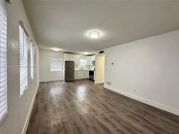 a view of empty room with wooden floor and window