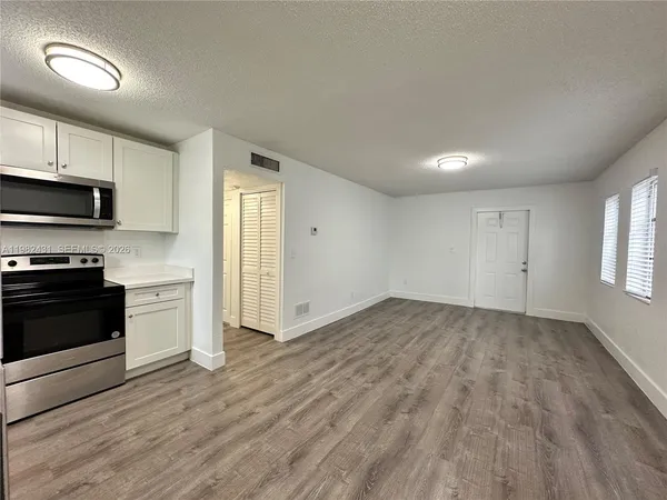 a view of a kitchen with wooden floor electronic appliances and windows