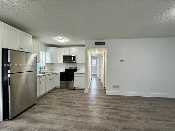 a kitchen with a refrigerator a stove top oven and cabinets