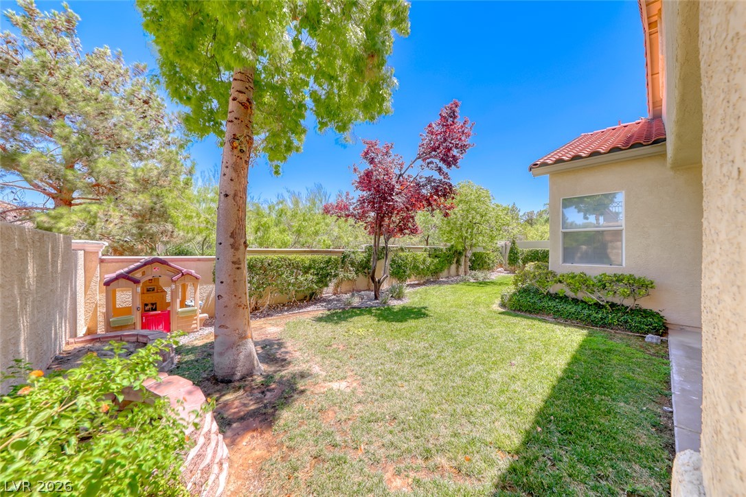 2122 Mooreview Street Henderson, NV 89012 - Photo 36 of 44 A vibrant green lawn and well-maintained shrubbery create a private, serene backyard oasis.