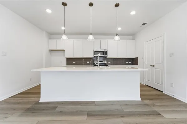 a view of kitchen with stainless steel appliances granite countertop cabinets and wooden floor