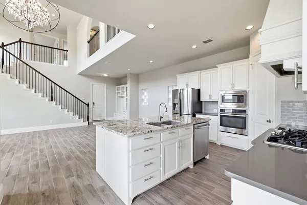 a view of a kitchen with stainless steel appliances kitchen island wooden floor and living room view