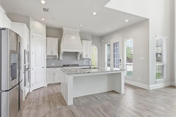a kitchen with stainless steel appliances kitchen island granite countertop a sink stove and refrigerator