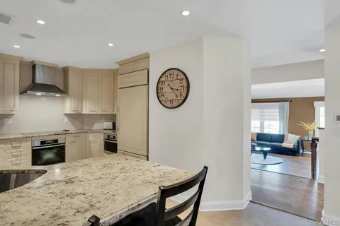 a kitchen with stainless steel appliances granite countertop a sink dishwasher and a flat screen tv