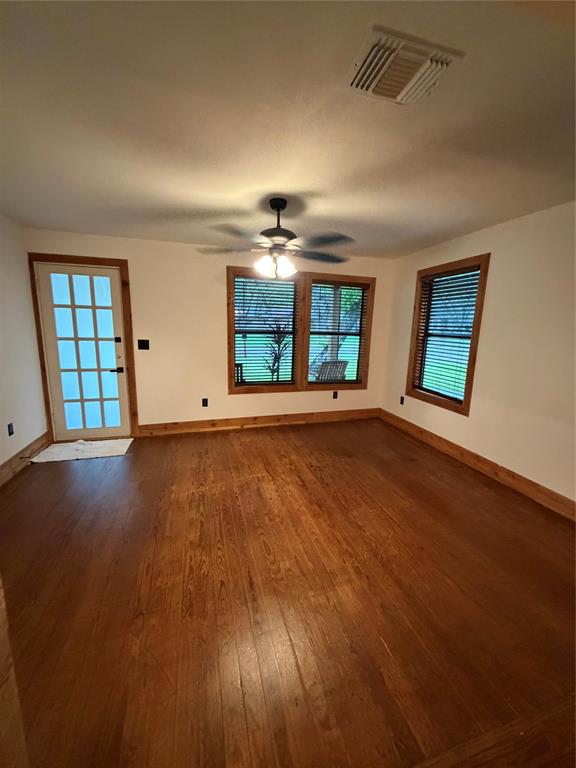 1605 South Houston Street Kaufman, TX 75142 - Photo 12 of 27 an empty room with wooden floor and windows