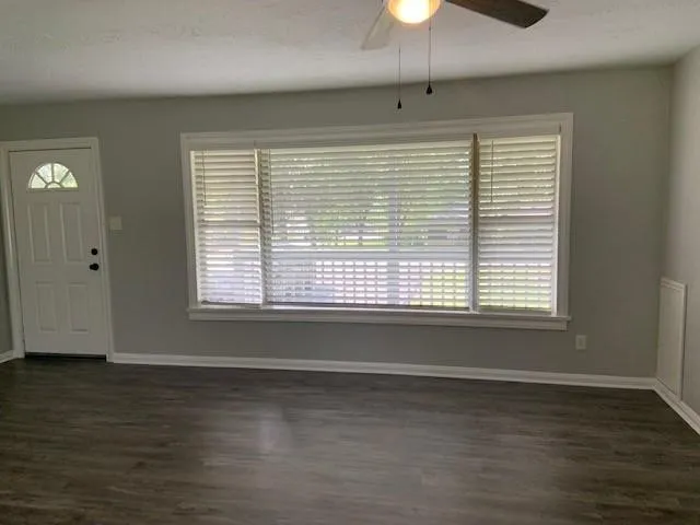 a view of an empty room with a window and wooden floor