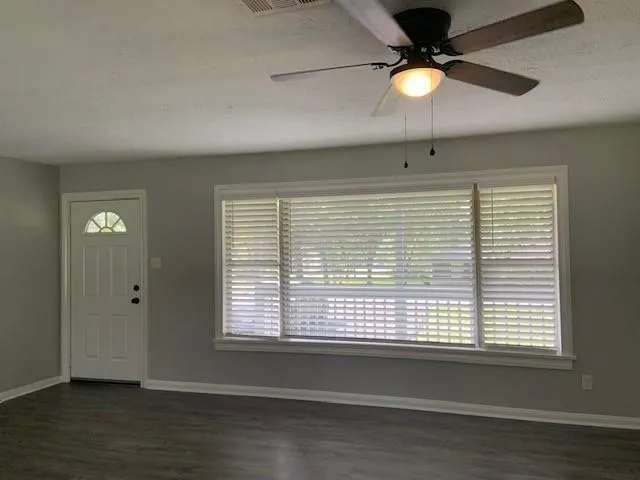 a view of an empty room with wooden floor and a window