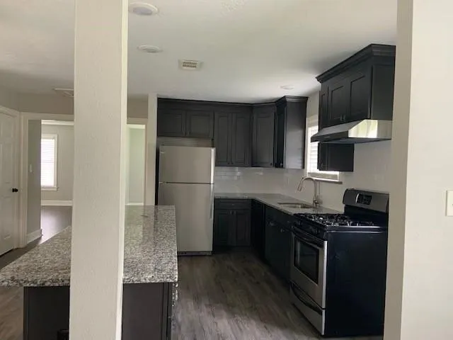 a kitchen with stainless steel appliances granite countertop a stove a refrigerator and a sink