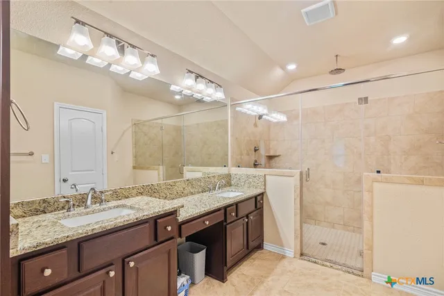 a bathroom with a granite countertop sink a large mirror and a shower