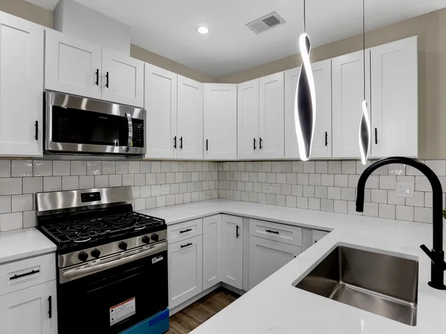 a kitchen with granite countertop white cabinets stainless steel appliances and a sink