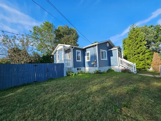 a view of a brick house with a big yard and large trees