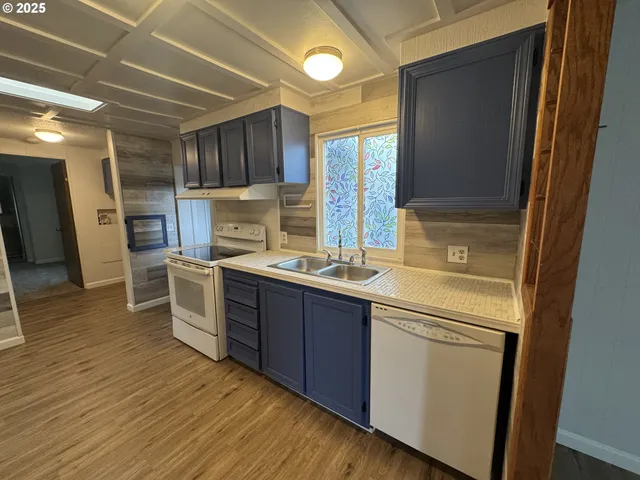 a kitchen with stainless steel appliances granite countertop a sink a stove a refrigerator with wooden cabinets and wooden floor