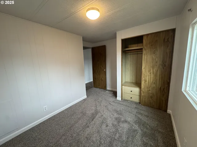 an empty room with closet and windows
