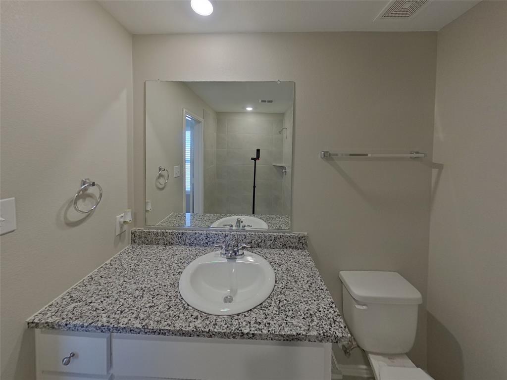 116 Cornstalk Lane Princeton, TX 75407 - Photo 8 of 17 a bathroom with a granite countertop sink a toilet and a mirror