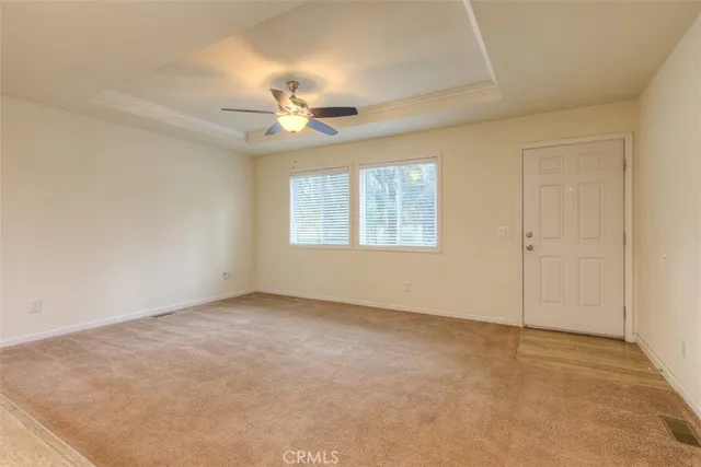 an empty room with chandelier fan and windows