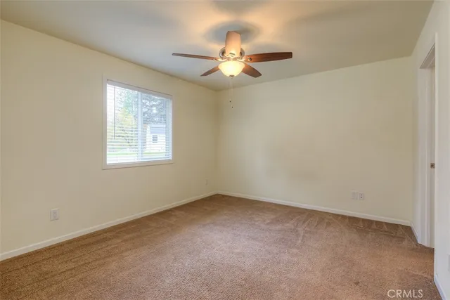 an empty room with windows and fan