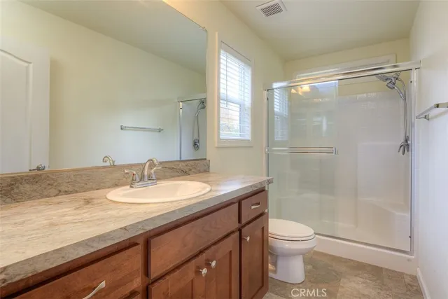 a bathroom with a granite countertop sink toilet a mirror and shower