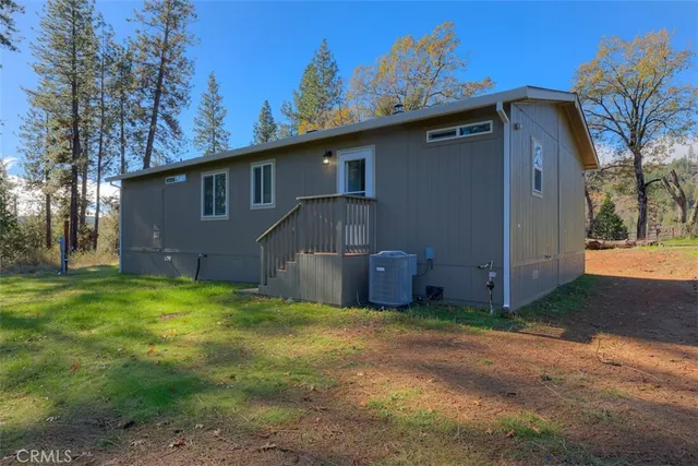 a backyard of a house with wooden fence and large trees