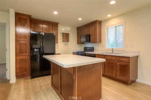 a kitchen with kitchen island granite countertop stainless steel appliances cabinets a sink and a window