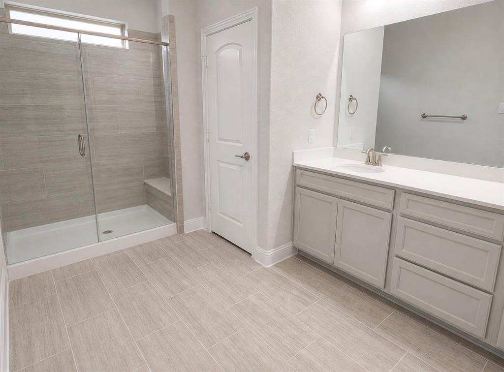 7849 Sunset Boulevard Rowlett, TX 75088 - Photo 8 of 13 Spacious bathroom featuring a glass-enclosed shower with a built-in bench, full vanity with dual sinks, light-toned cabinetry, and tile flooring