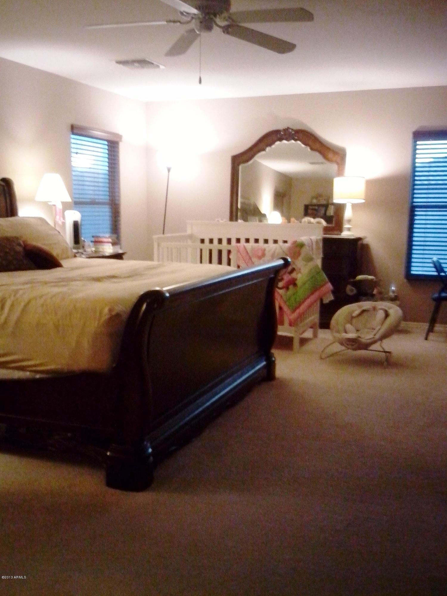 9427 West Monte Vista Road Phoenix, AZ 85037 - Photo 8 of 13 a spacious bedroom with a bed and a mirror