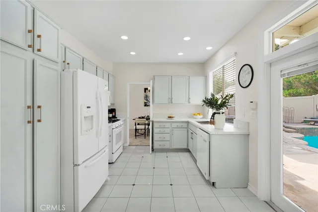 a kitchen with white cabinets and window