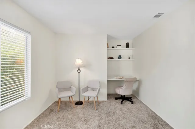 a view of a workspace with furniture and a window