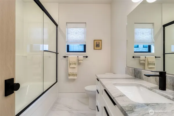 a bathroom with a granite countertop sink a toilet and a shower