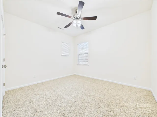 an empty room with ceiling fan and window