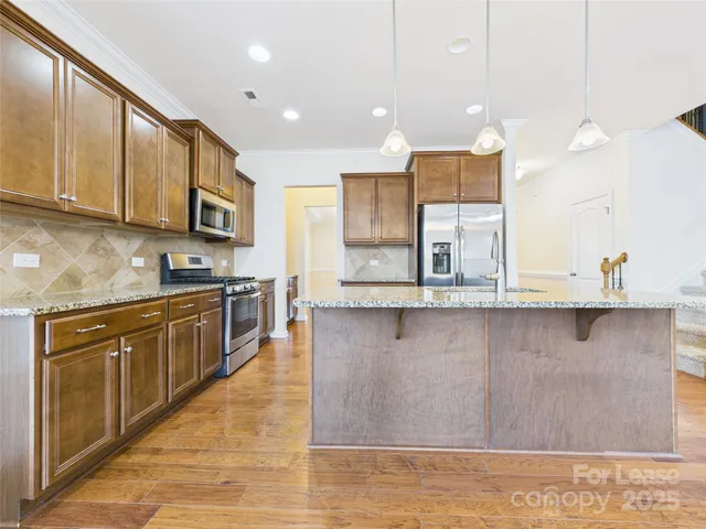 a kitchen with stainless steel appliances granite countertop a sink a stove and a wooden cabinets