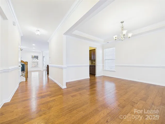 a view of a hallway with wooden floor and a kitchen