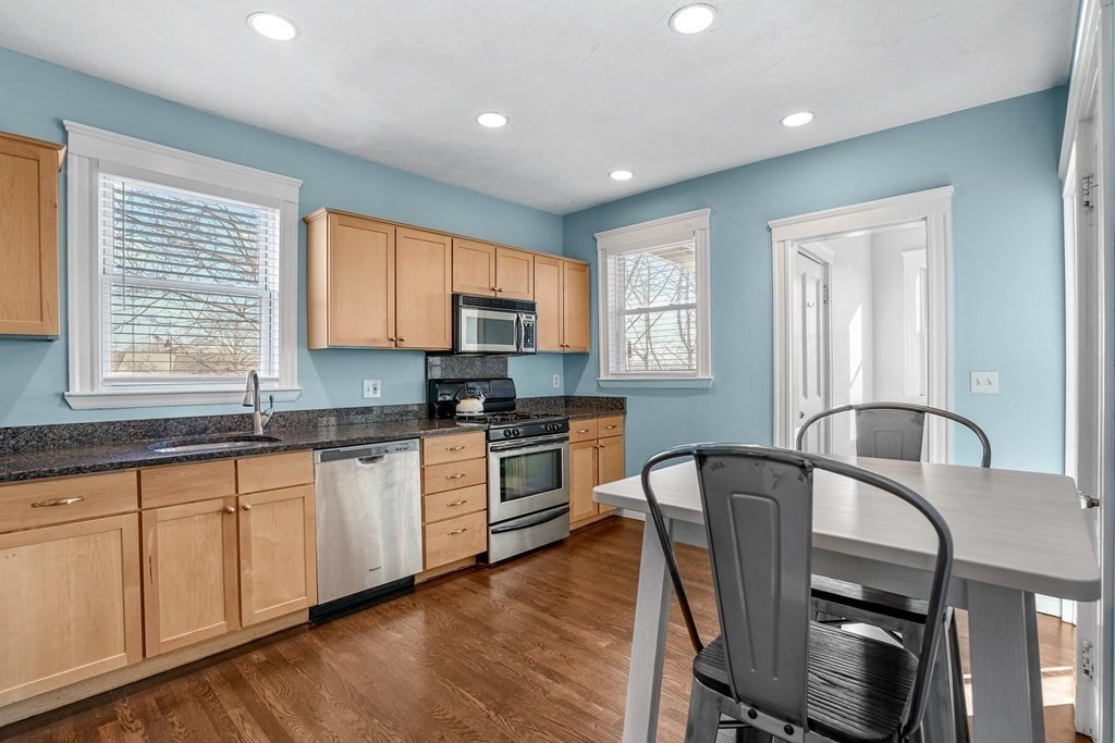 12 Clover Street, Unit 2 Boston, MA 02122 - Photo 6 of 13 a kitchen with granite countertop white cabinets a sink a window and stainless steel appliances