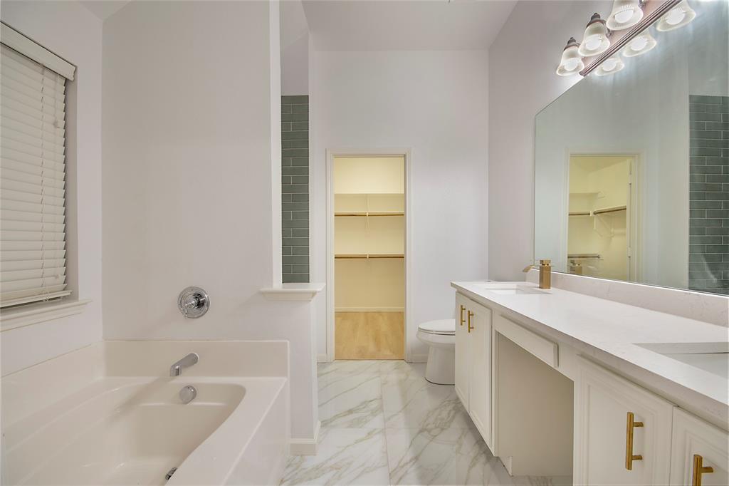 549 Hickory Lane Fate, TX 75087 - Photo 13 of 22 a bathroom with a tub sink and mirror