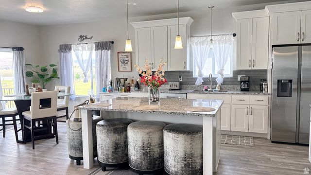 7889 Bristlecone Road Eagle Mountain, UT 84005 - Photo 15 of 42 Open-concept kitchen and dining area featuring a central island with a granite-style countertop, white cabinetry with crown molding, and stainless steel appliances