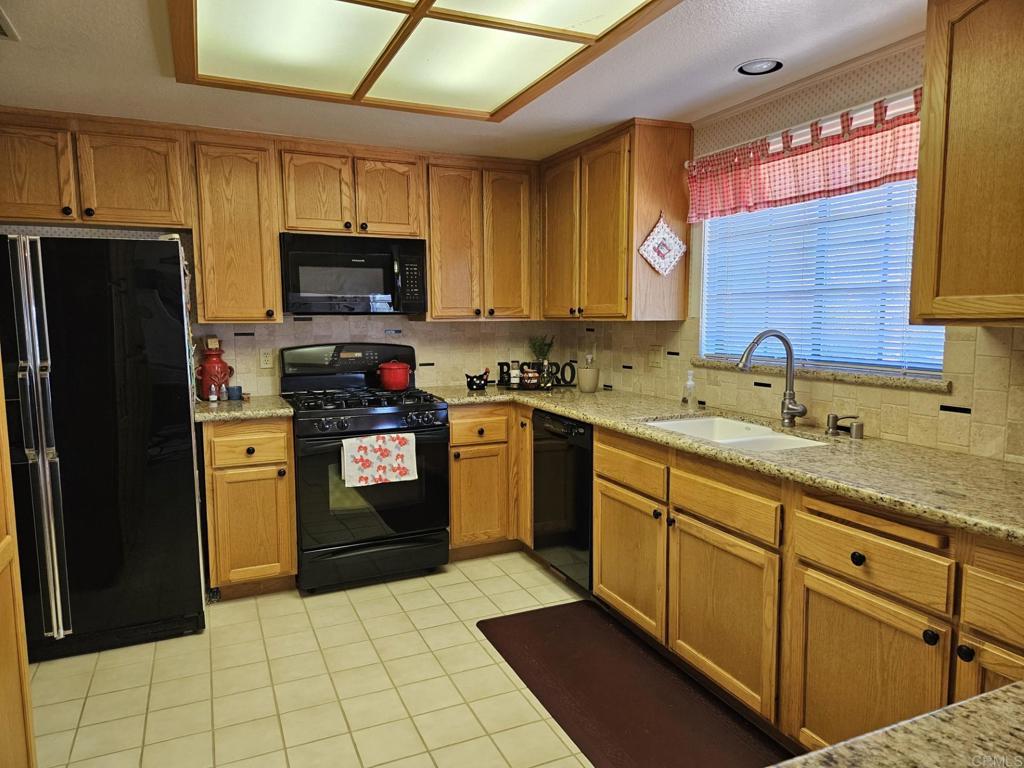 28124 Mountain Meadow Road Escondido, CA 92026 - Photo 8 of 31 a kitchen with a sink a stove top oven a refrigerator cabinets and a window