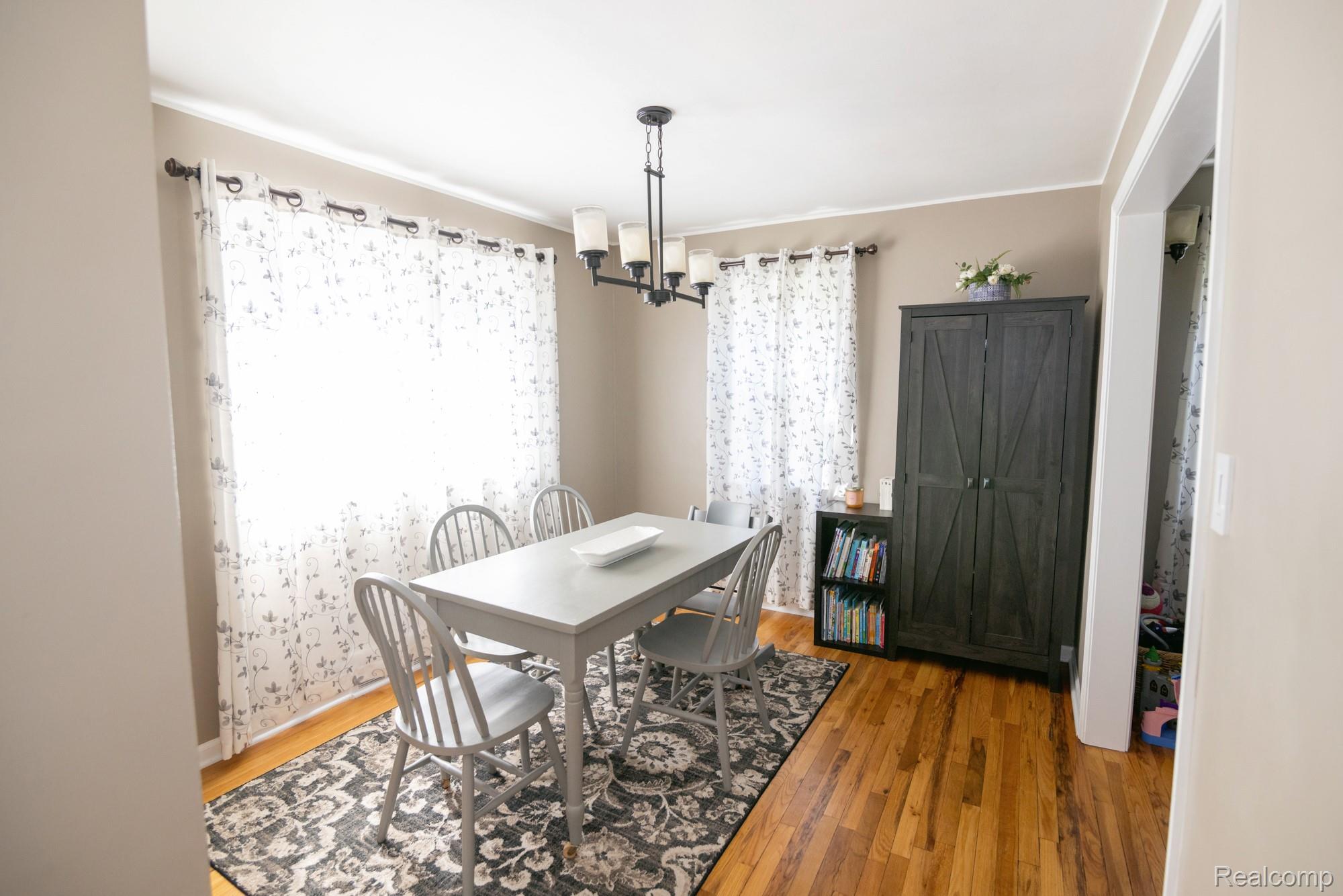 3757 Cone Avenue Rochester, MI 48309 - Photo 8 of 45 Dining area featuring wood-finish flooring, two large windows, a black five-light chandelier, and light-toned wall paint