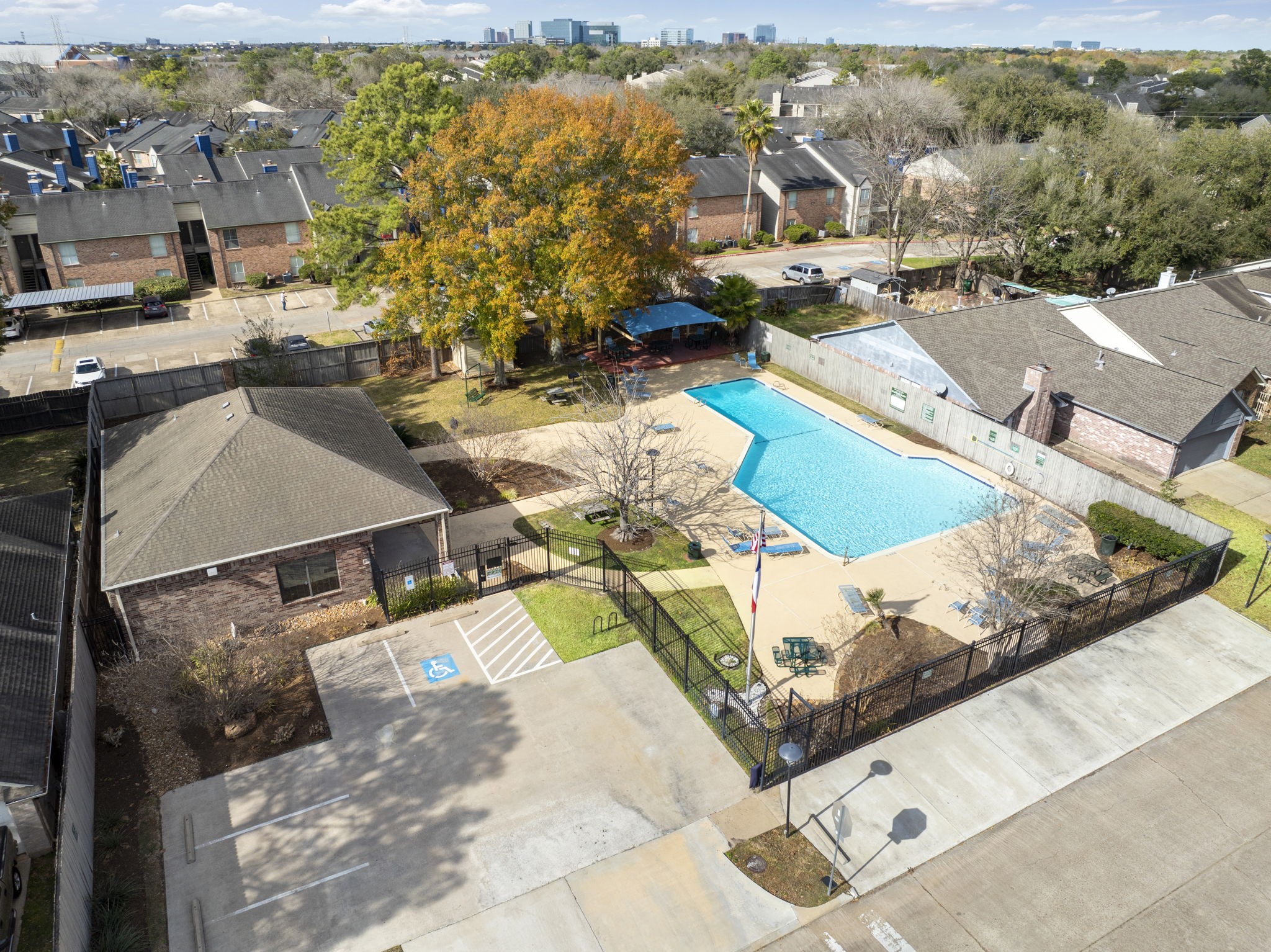 2110 Paso Rello Drive Houston, TX 77077 - Photo 41 of 41 This photo showcases a well-maintained community pool with lounge chairs and a shaded seating area. Surrounding the pool are townhouses, mature trees, and ample parking space, offering a peaceful and community-oriented environment.