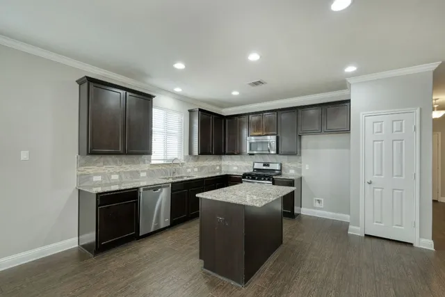 a kitchen with stainless steel appliances granite countertop a sink stove and refrigerator