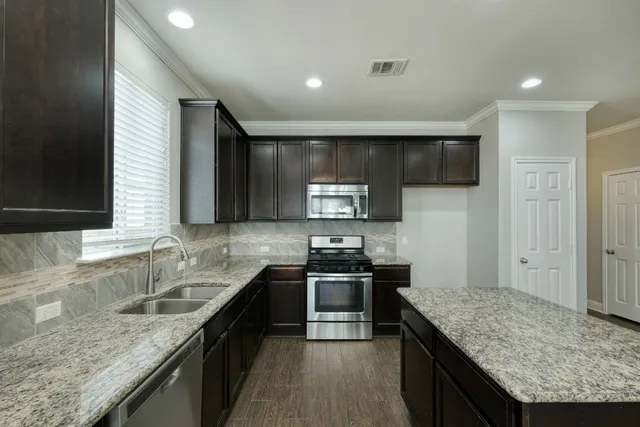 a kitchen with stainless steel appliances granite countertop sink stove microwave and cabinets